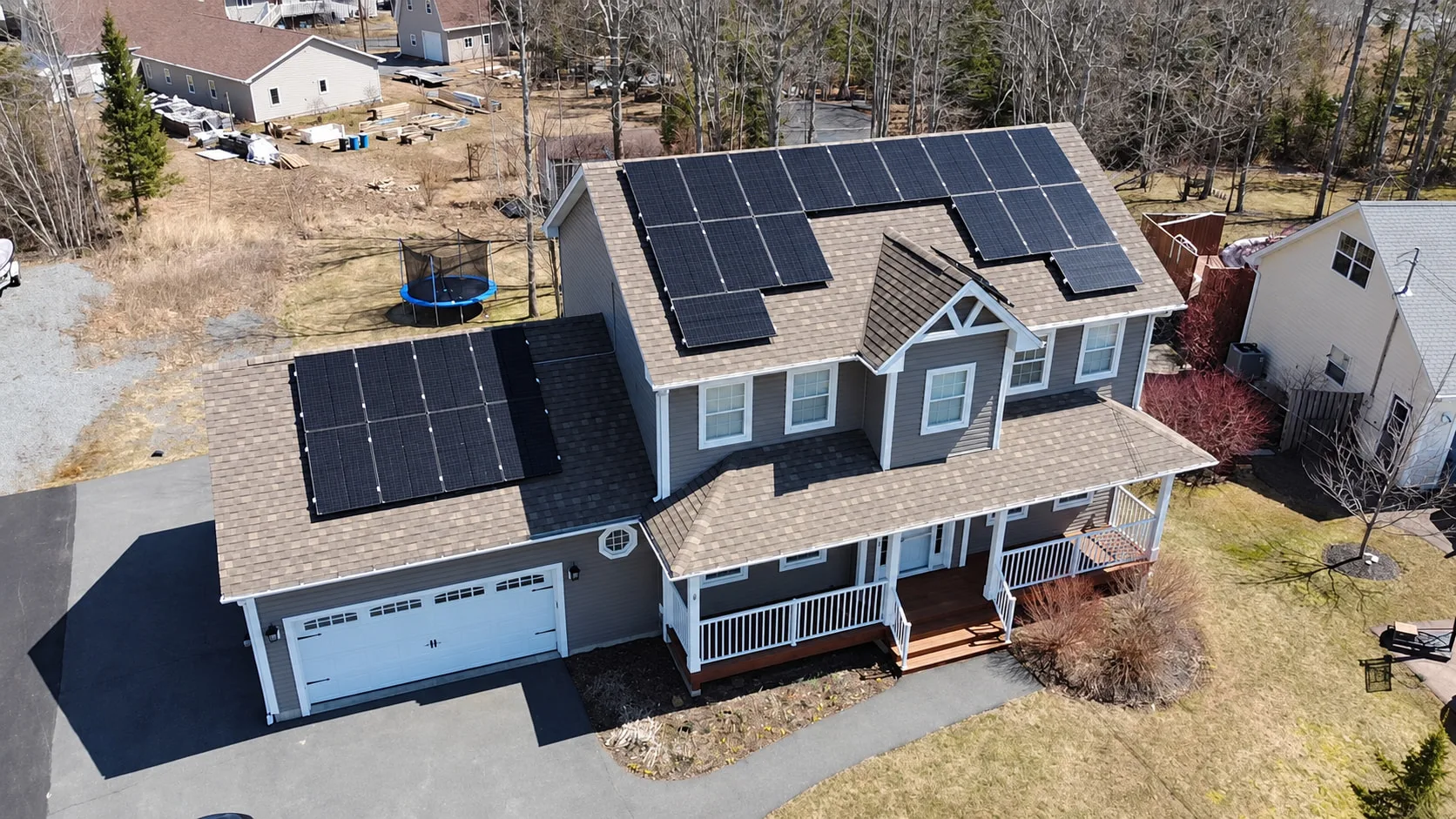 Aerial view of a two-storey grey home with solar panels on several roof faces