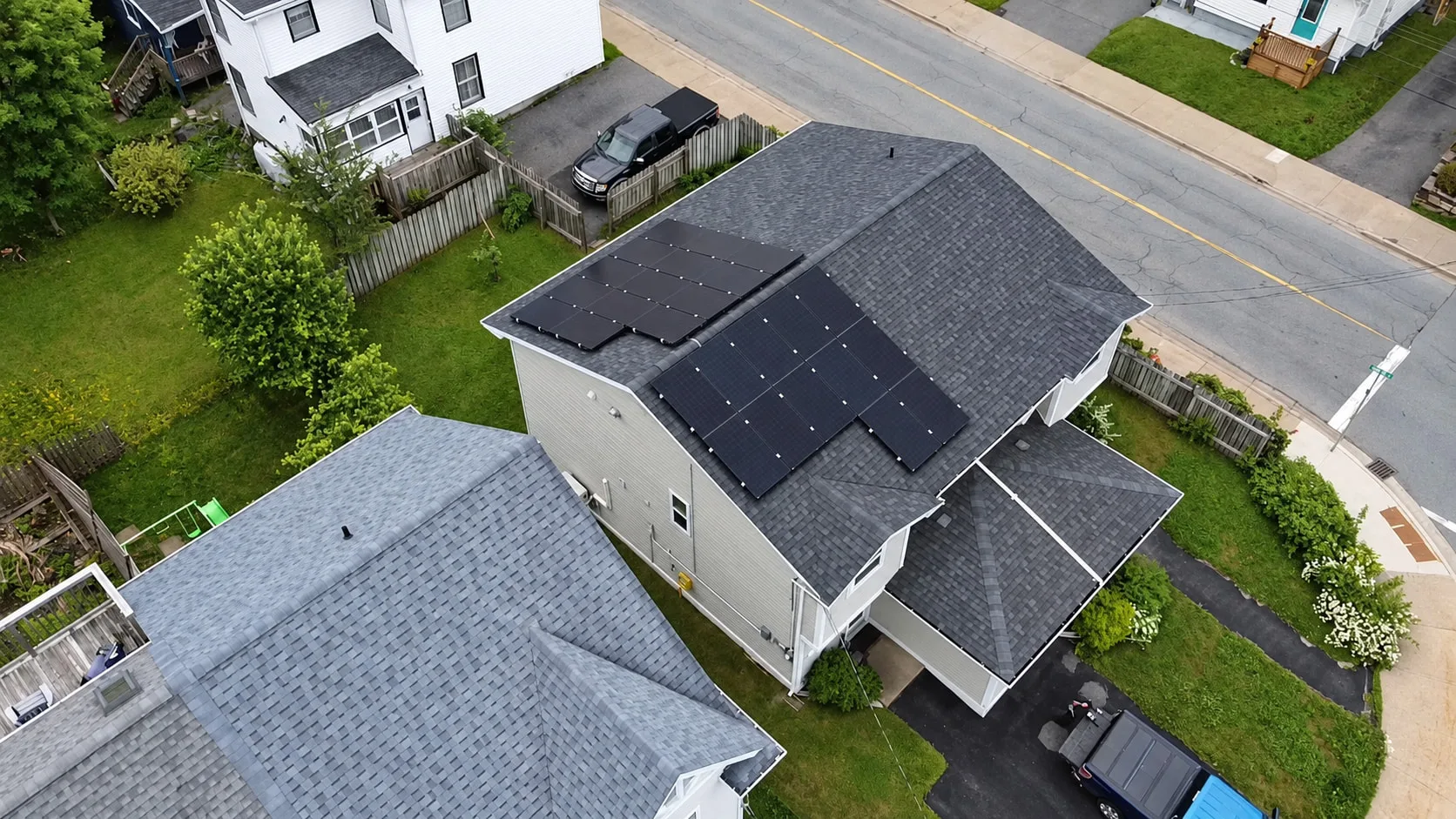 Suburban home with black solar panels on a grey shingled roof