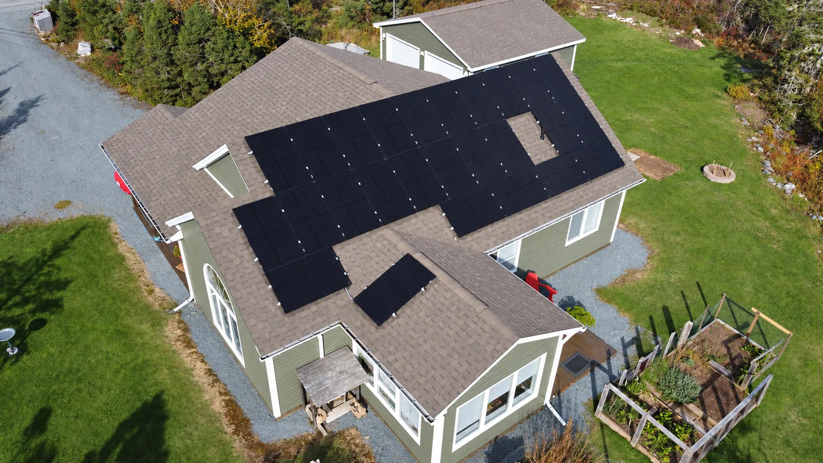 Home with an L-shaped solar array on its roof, surrounded by lawn